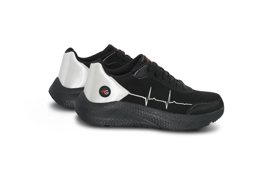Flatlay of MoxieGalia StandFX 12 black and white sneakers with signature white ECG line across the side, black outsole, and red MG branding — displayed on white background.