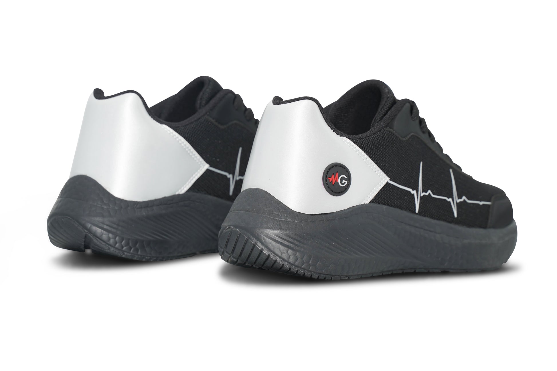 Rear and side view of MoxieGalia StandFX 12 sneakers in black and white with white ECG line across the side, red MG circular logo at the heel, and chunky black sole — displayed on white background.